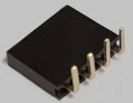 A black integrated circuit with four metallic pins, resting on a grey surface.