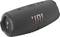 Portable grey Bluetooth speaker with JBL logo, cylindrical shape, side bass speaker, black buttons on top.