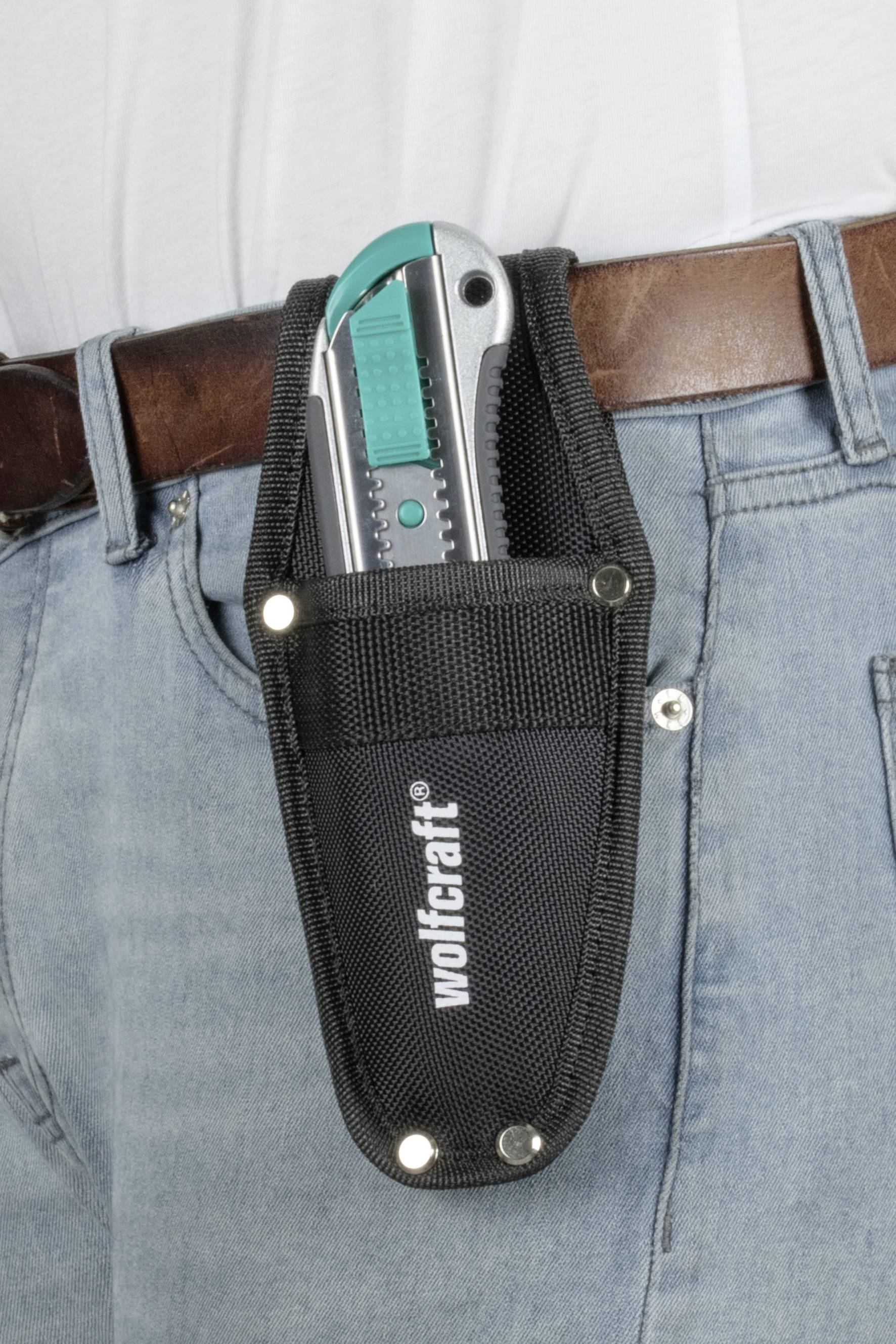 The image shows a penknife in a black holster, attached to a belt on a pair of jeans.