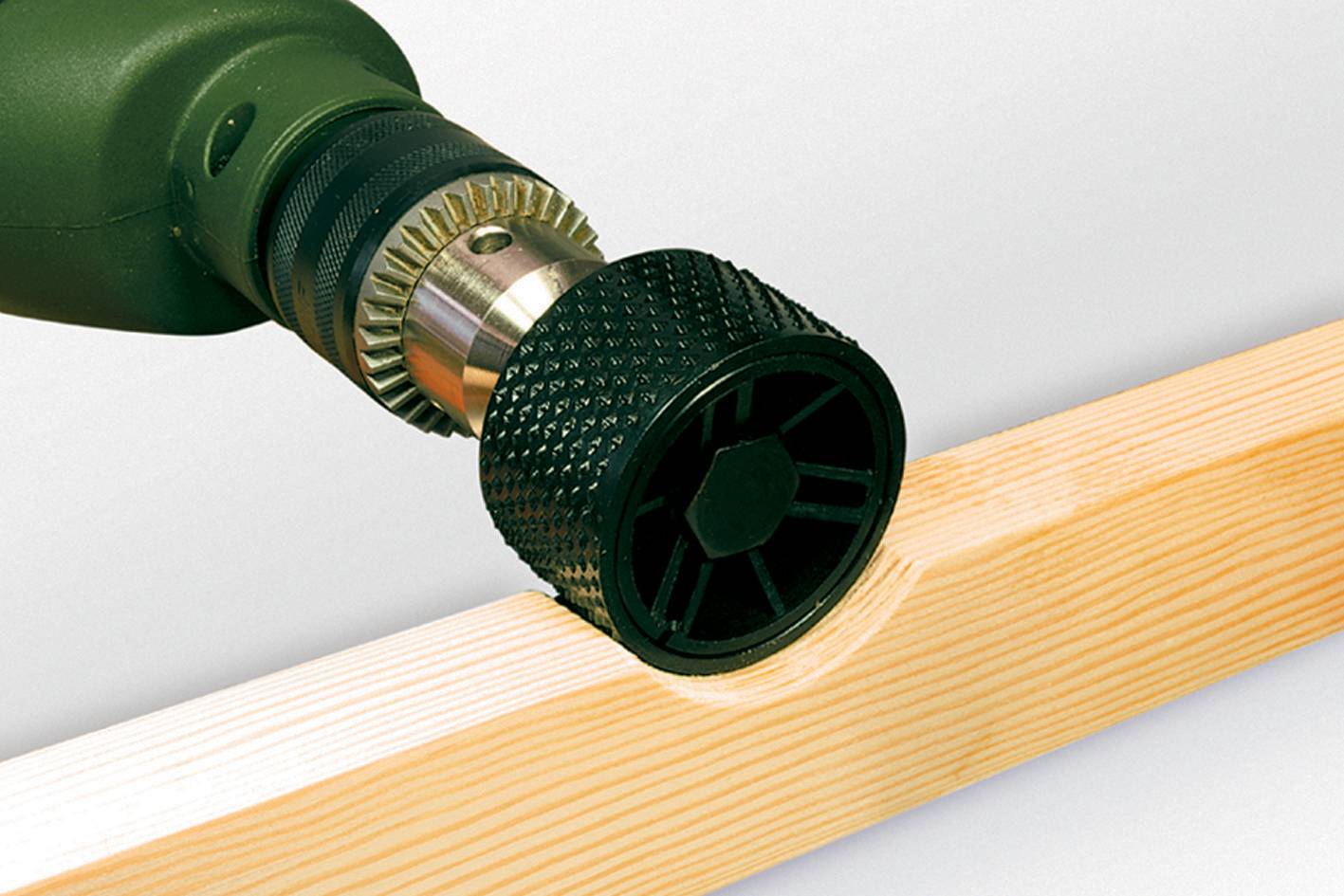 A drill with a grinding attachment is machining the edge of a piece of wood.