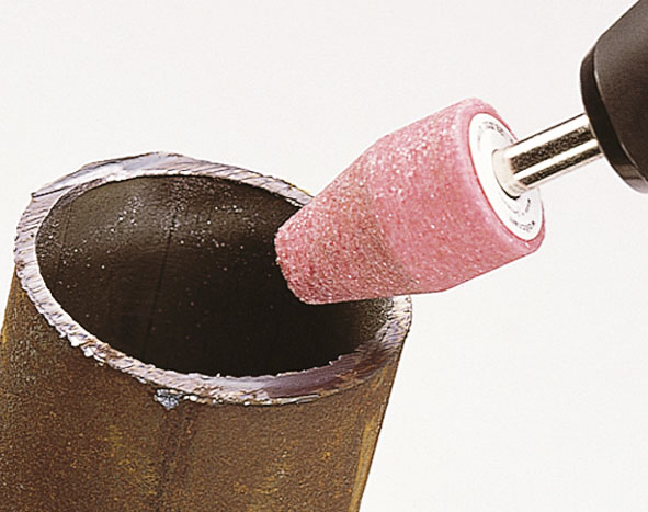 Close-up of a brown tube being polished internally with a rotating grinding attachment.