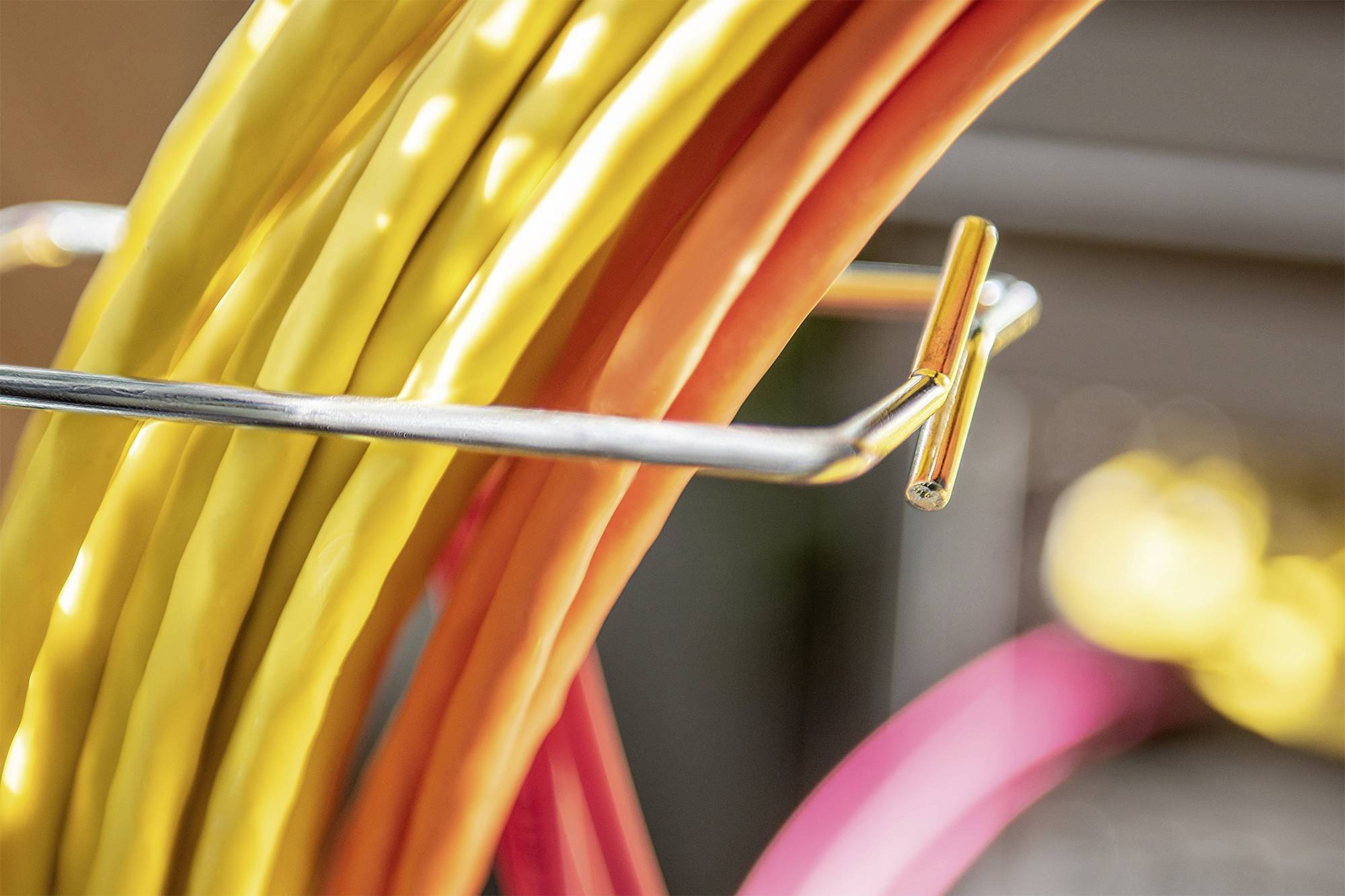 Several coloured cables are organised in a metal holder. They run closely side by side, with yellow, red, and pink cables visible.