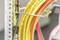 Several yellow and pink cables are neatly arranged and secured with a metal bracket to a grid.