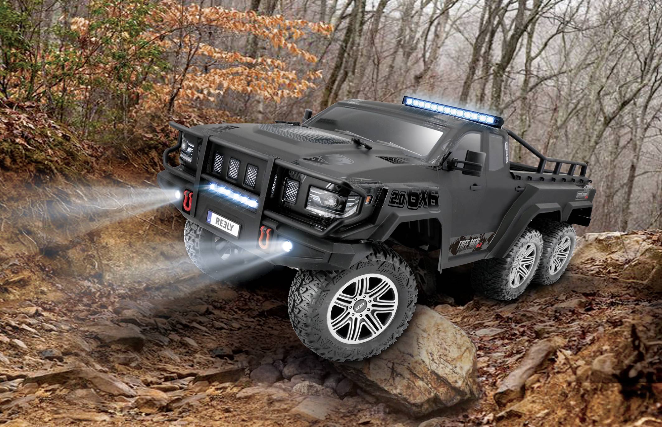 A black, six-wheeled off-road vehicle with gleaming headlights navigates a rocky trail lined with trees in the forest.