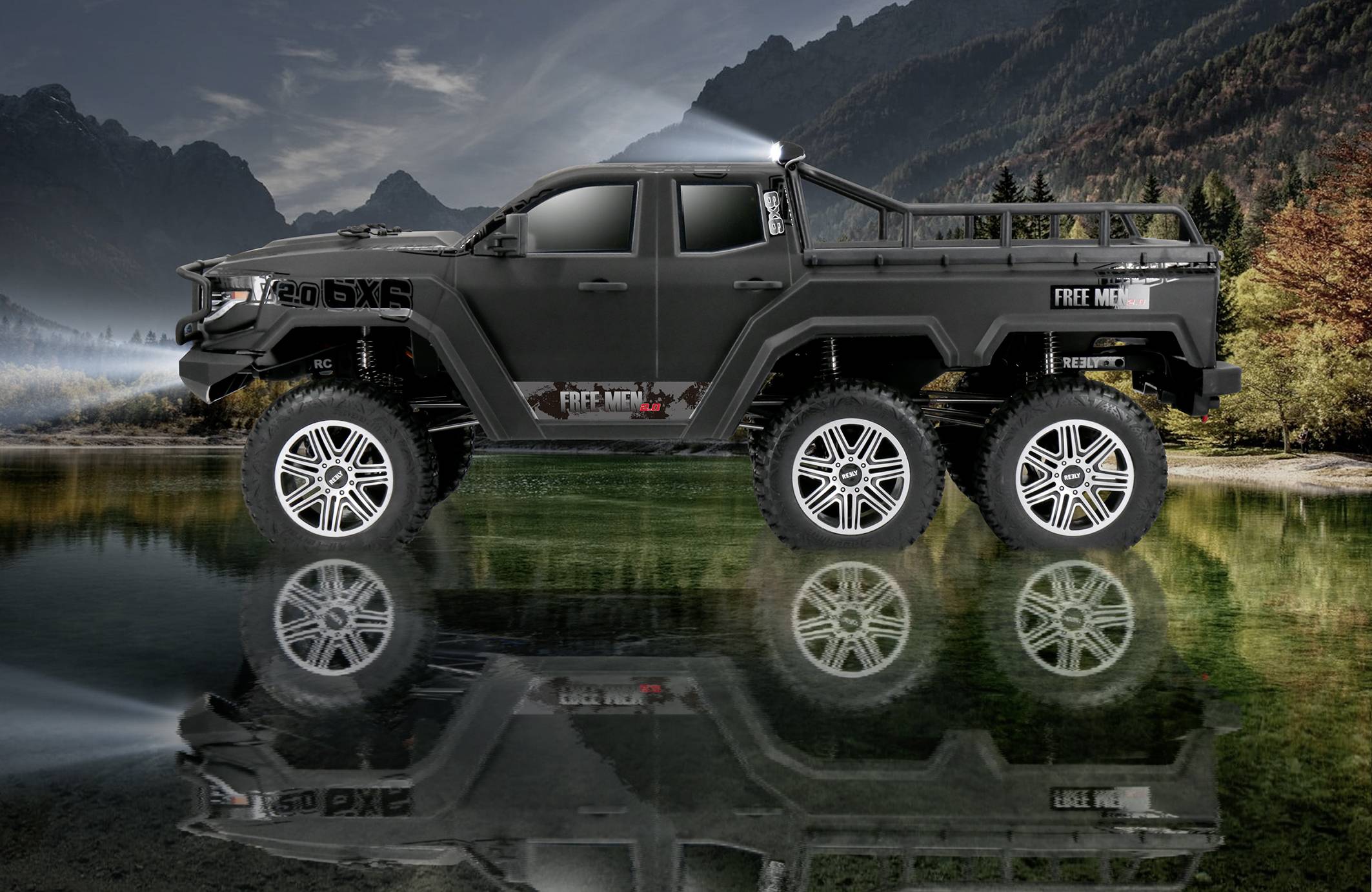 A large, black six-wheeled off-road vehicle stands on the shore of a lake, with its reflection mirrored in the water and misty mountains in the background.
