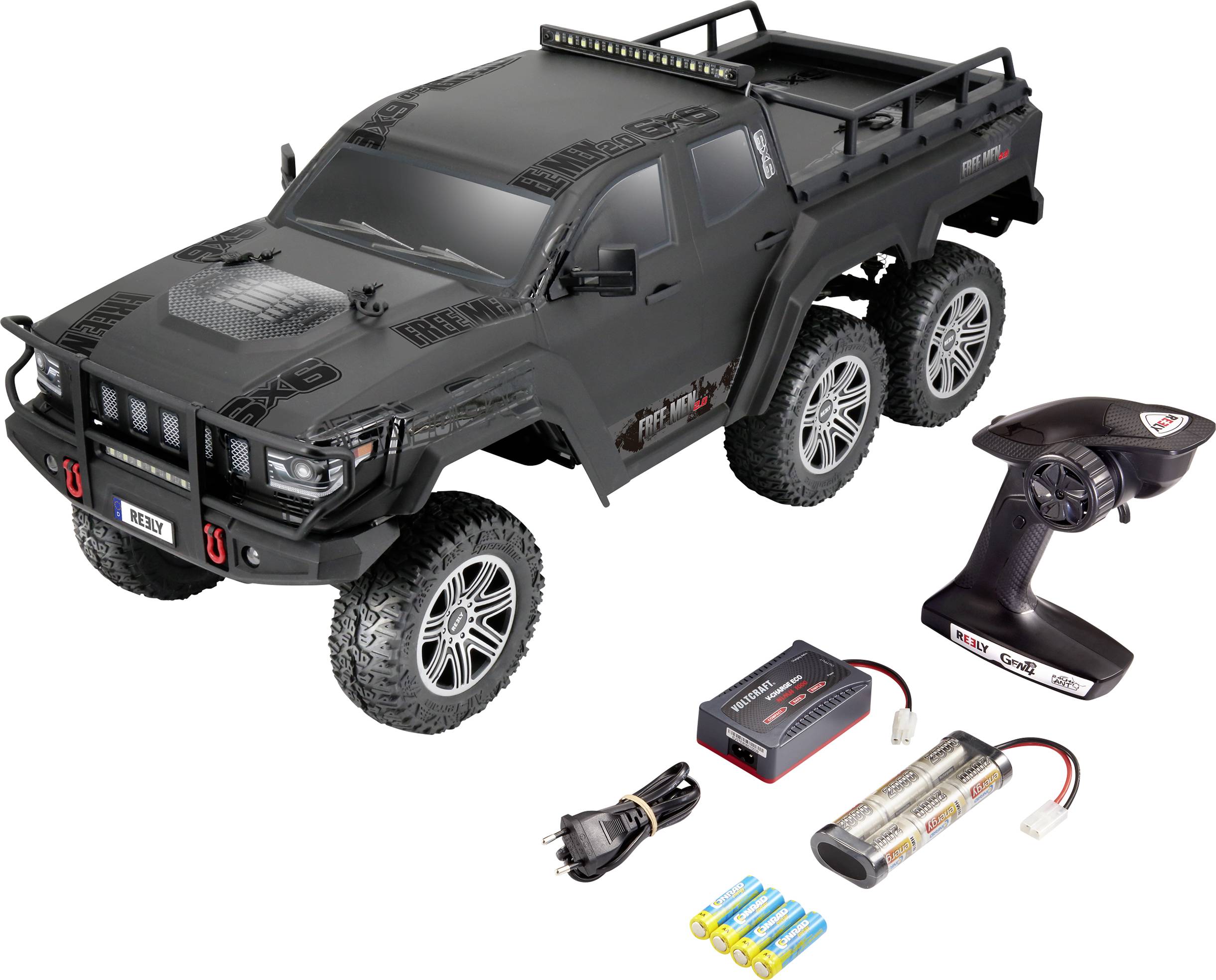Remote-controlled, six-wheeled, black off-road truck with accessories: remote control, charger, battery packs, and cables.