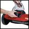 A person is inserting a battery into a red, electric garden tool. The device has large wheels and is likely a lawnmower.