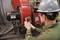 A technician is using a thermal imaging camera to check the temperature of a red electric motor. The motor is running normally.