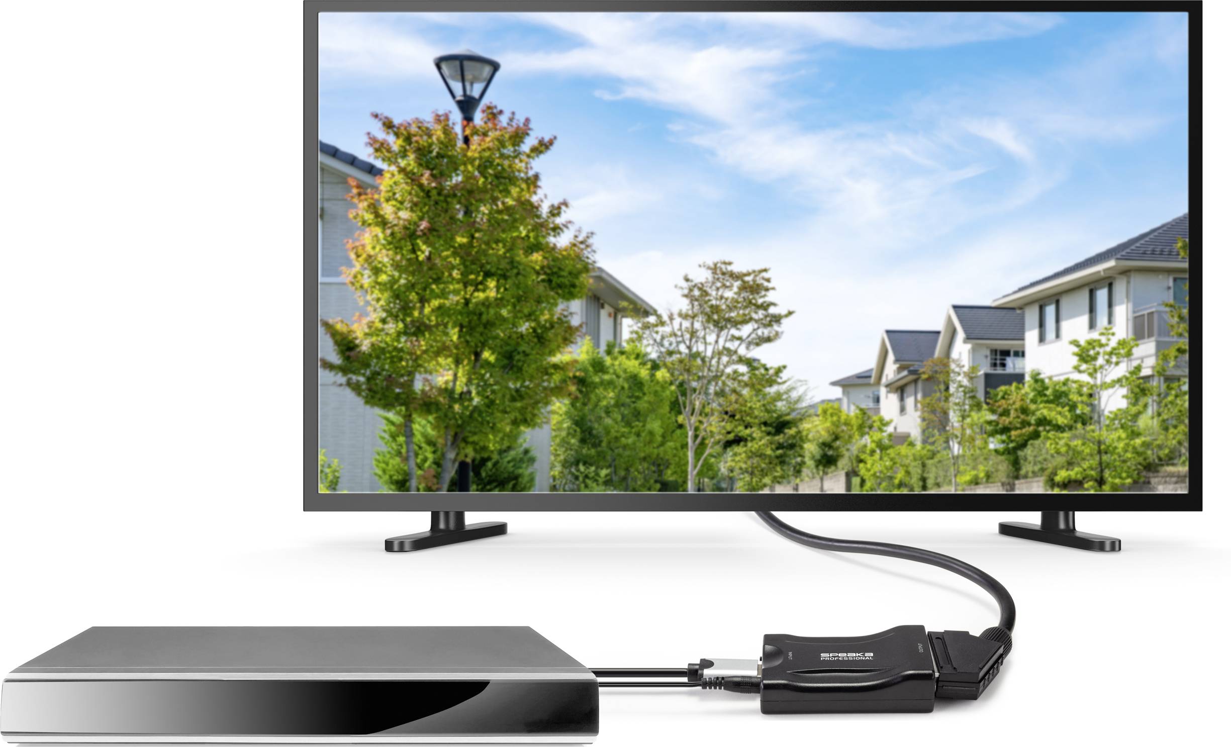 A television shows an image of houses and trees under a blue sky. A cable connects the television to a black device.