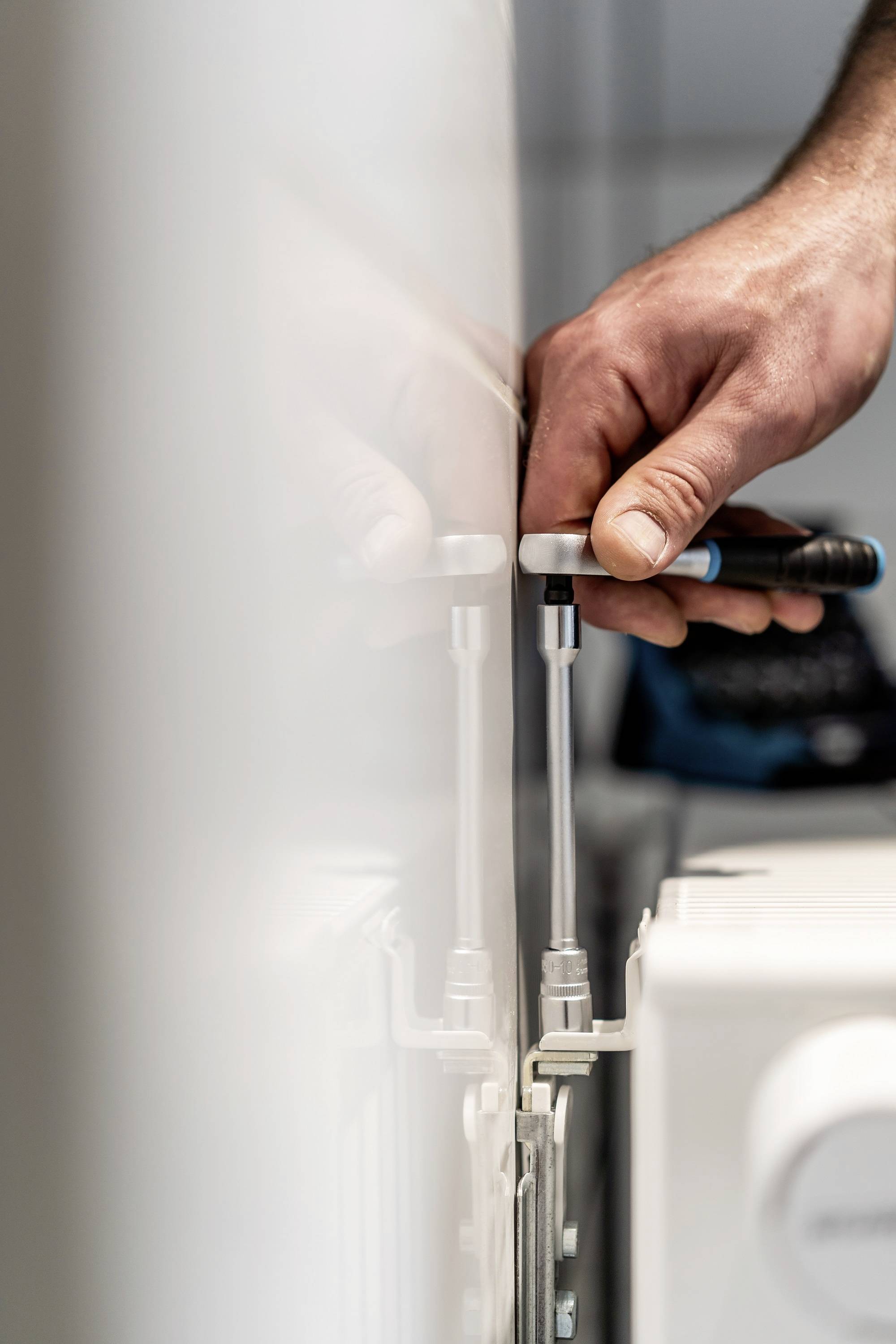 A person is securing the lid of a radiator thermostat. A screwdriver is being used.