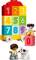 Two Lego minifigure children are playing with a colourful number train, which displays the numbers 0 to 9. A dog is sitting beside them.