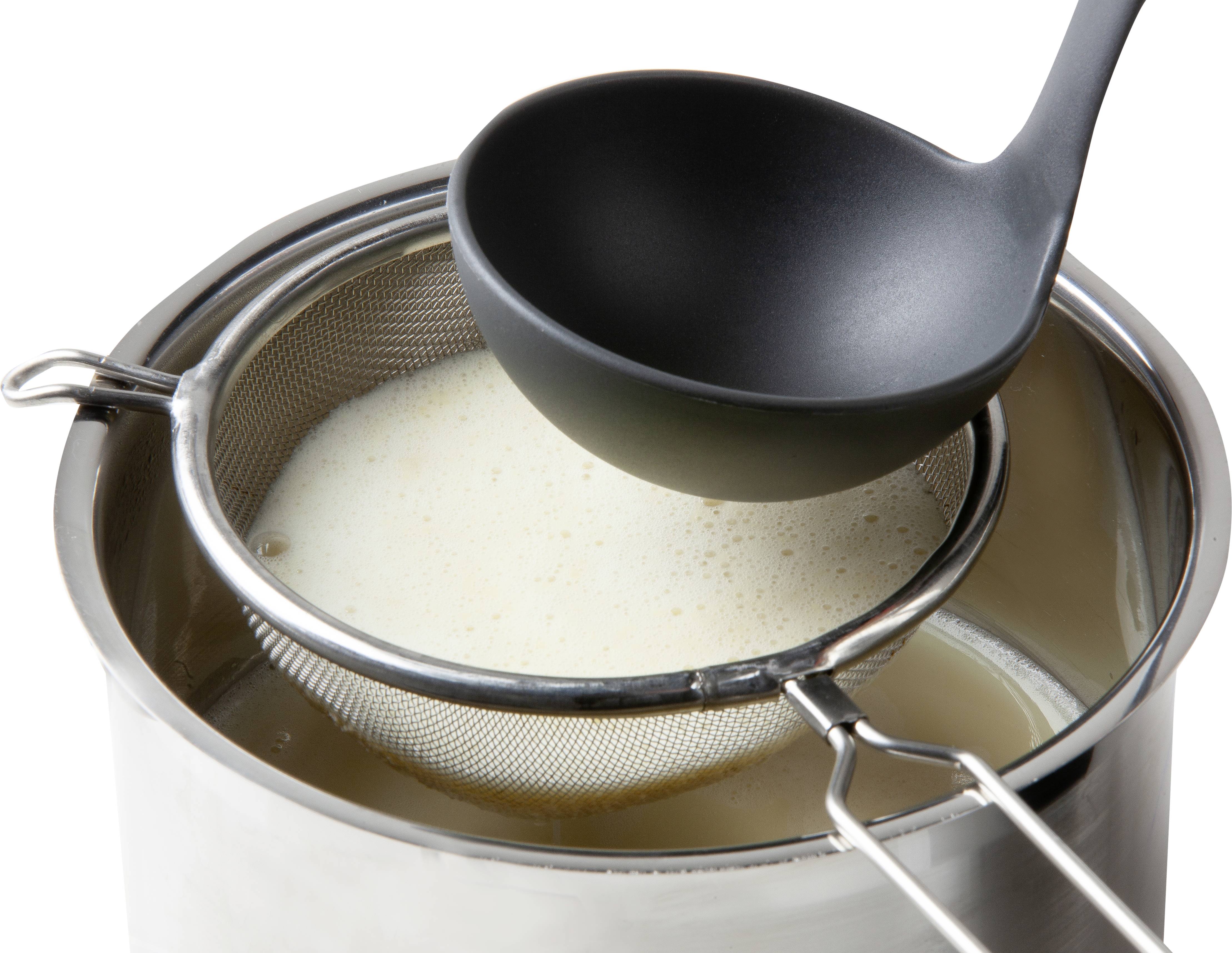 A saucepan of liquid being strained through a sieve. A black ladle rests on the sieve.