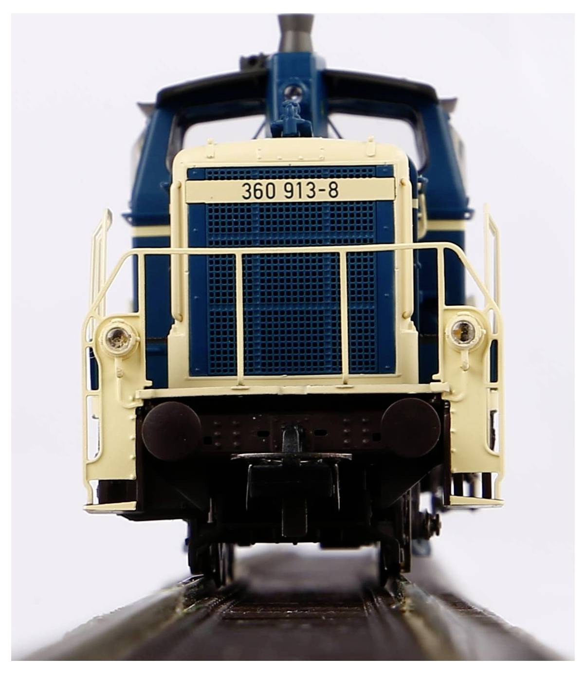 Close-up of a model locomotive in blue and beige on railway tracks, front view. Locomotive number '360 913-8'.