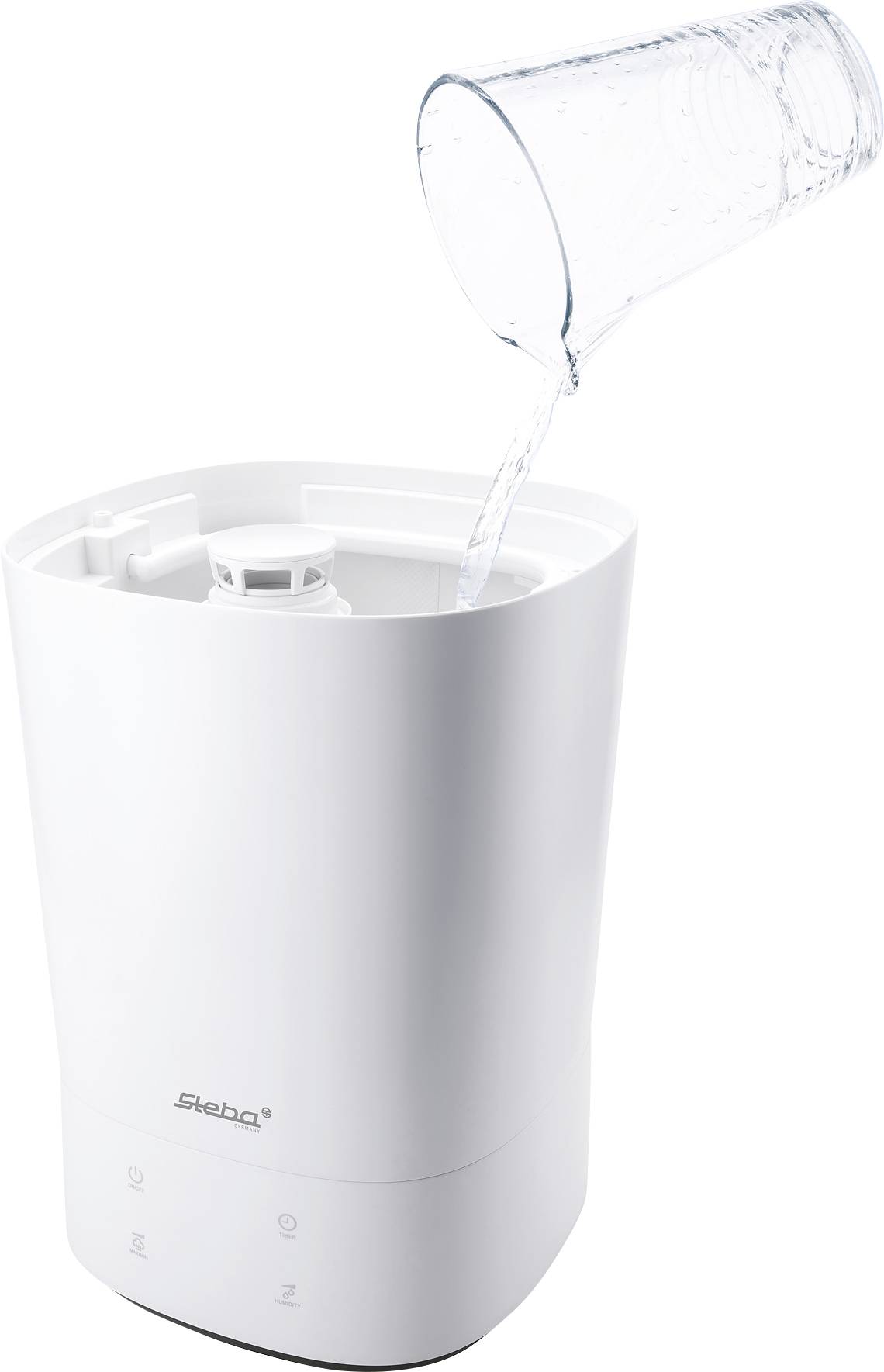 A white air humidifier is being filled with water from a measuring jug.