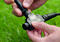 A person is holding a black cable with connectors in their hands. The background shows green grass.