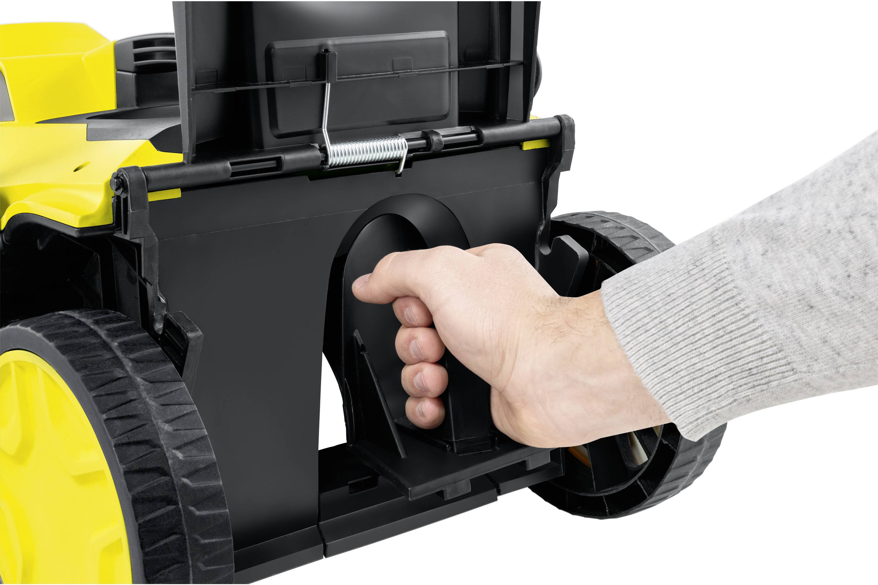A hand grasps the handle of a black and yellow device with wheels, presumably for operation or transportation.