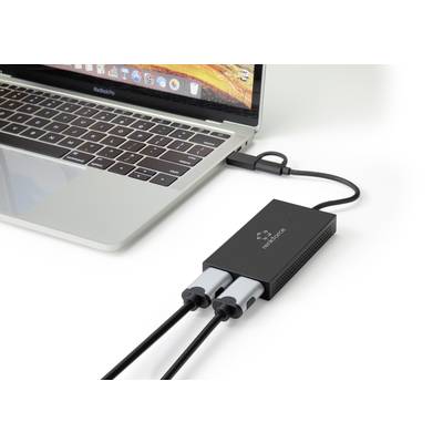 A laptop is connected to a black adapter that connects two cables. The adapter facilitates the connection of external devices.