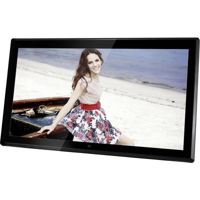 A smiling woman sits in a boat on the beach. She is wearing a sleeveless top and a floral-patterned skirt. The sea is visible in the background.