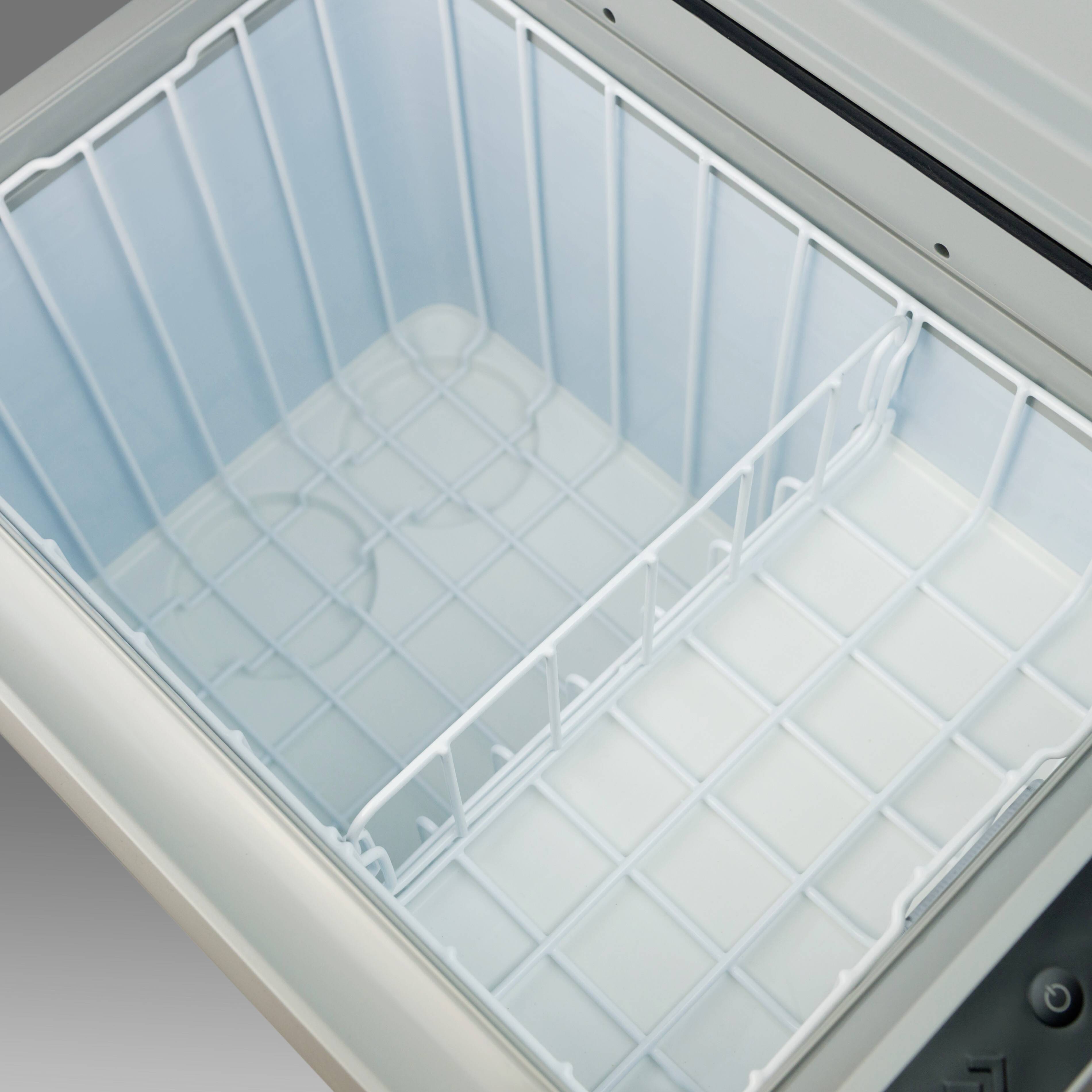 A blank, open freezer chest is shown from a bird's-eye view. The walls and floor are white.