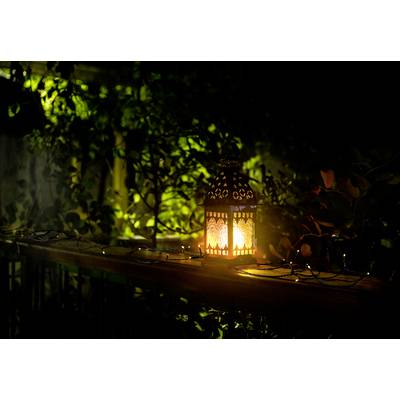 A decorative lantern sits on a wooden banister, radiating warm, yellow light. Leaves are visible in the background.