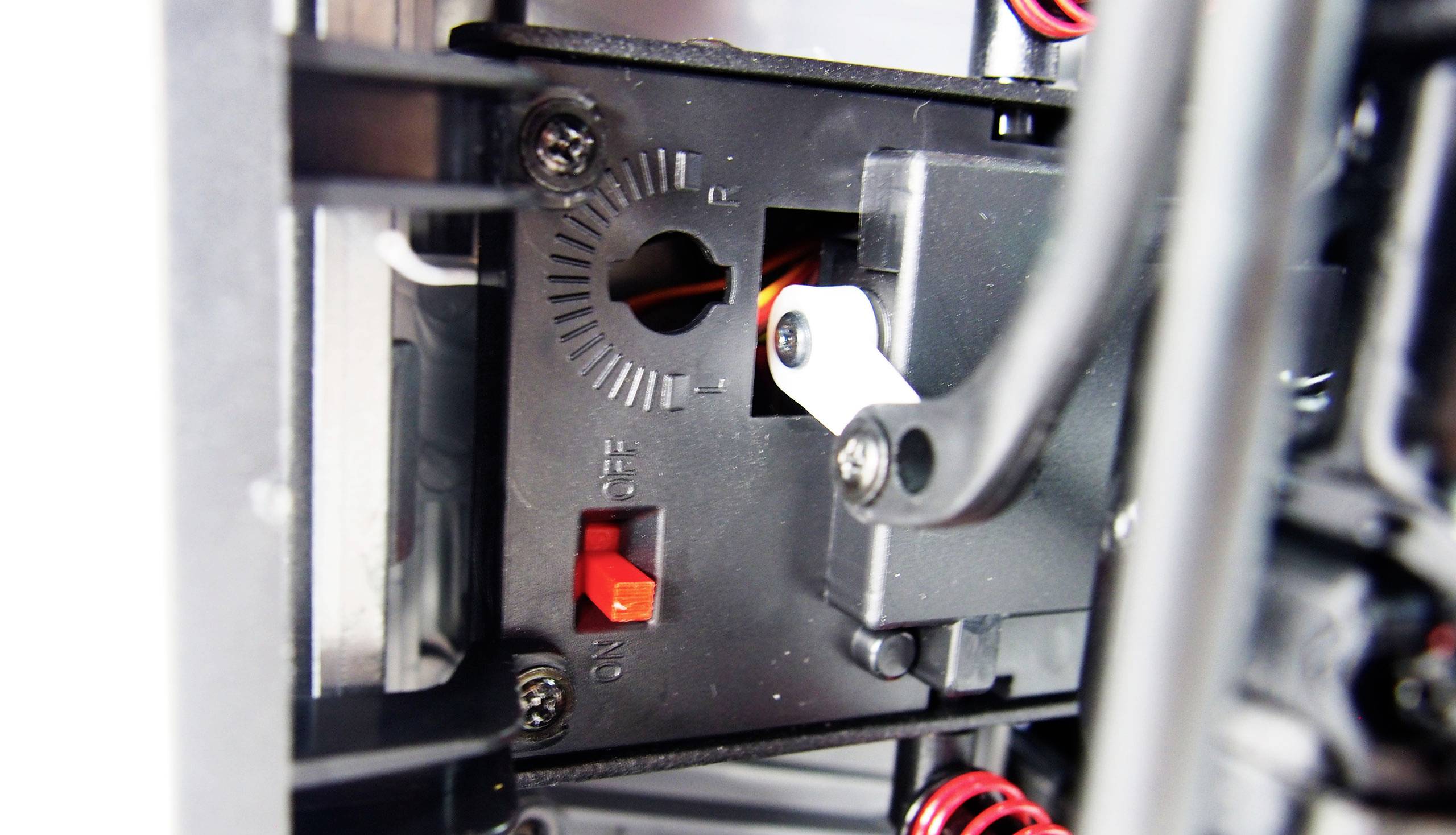 Close-up of a mechanical switch with a red lever in the 'Off' position, surrounded by metal struts and cables.