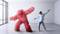 A person is wearing a VR headset and dancing next to a large, red, fluffy figure in a modern, empty room.