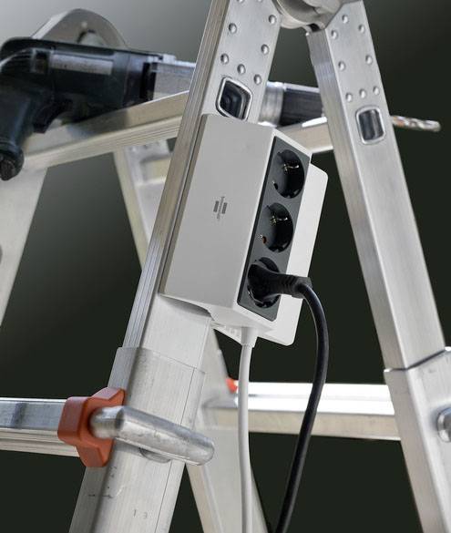 A three-socket extension lead is attached to an aluminium ladder. A drill is visible in the top left.