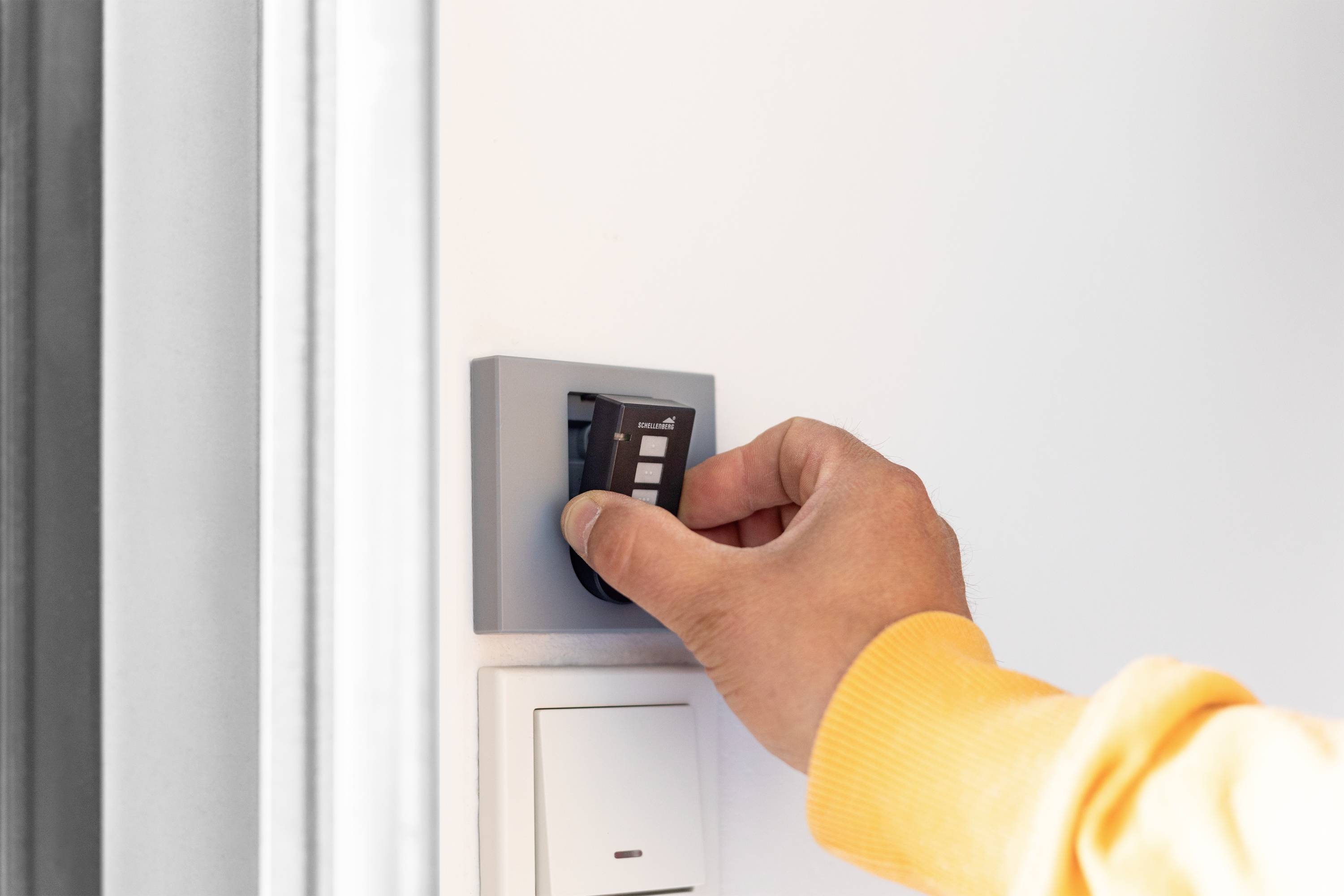 A hand inserts a key card into a wall switch. The person is wearing a yellow jumper. This could be part of an access control system.