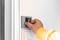 A hand inserts a key card into a wall switch. The person is wearing a yellow jumper. This could be part of an access control system.