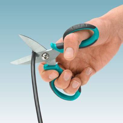 A hand holds scissors and cuts a black cable, against a blue background.