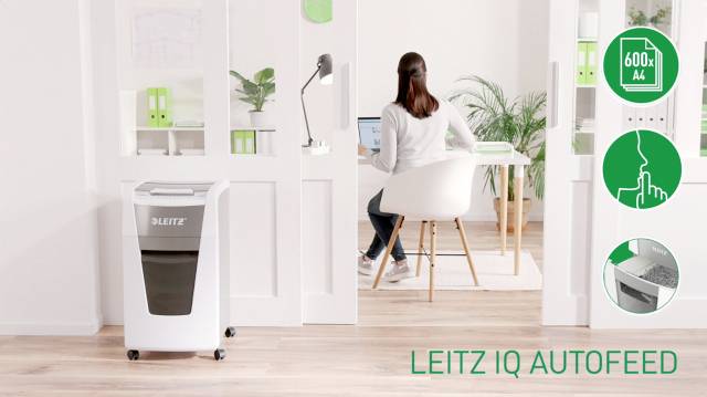 A woman is working at a desk in a modern office. A Leitz paper shredder is in the foreground. Symbols indicate its capacity and functions.