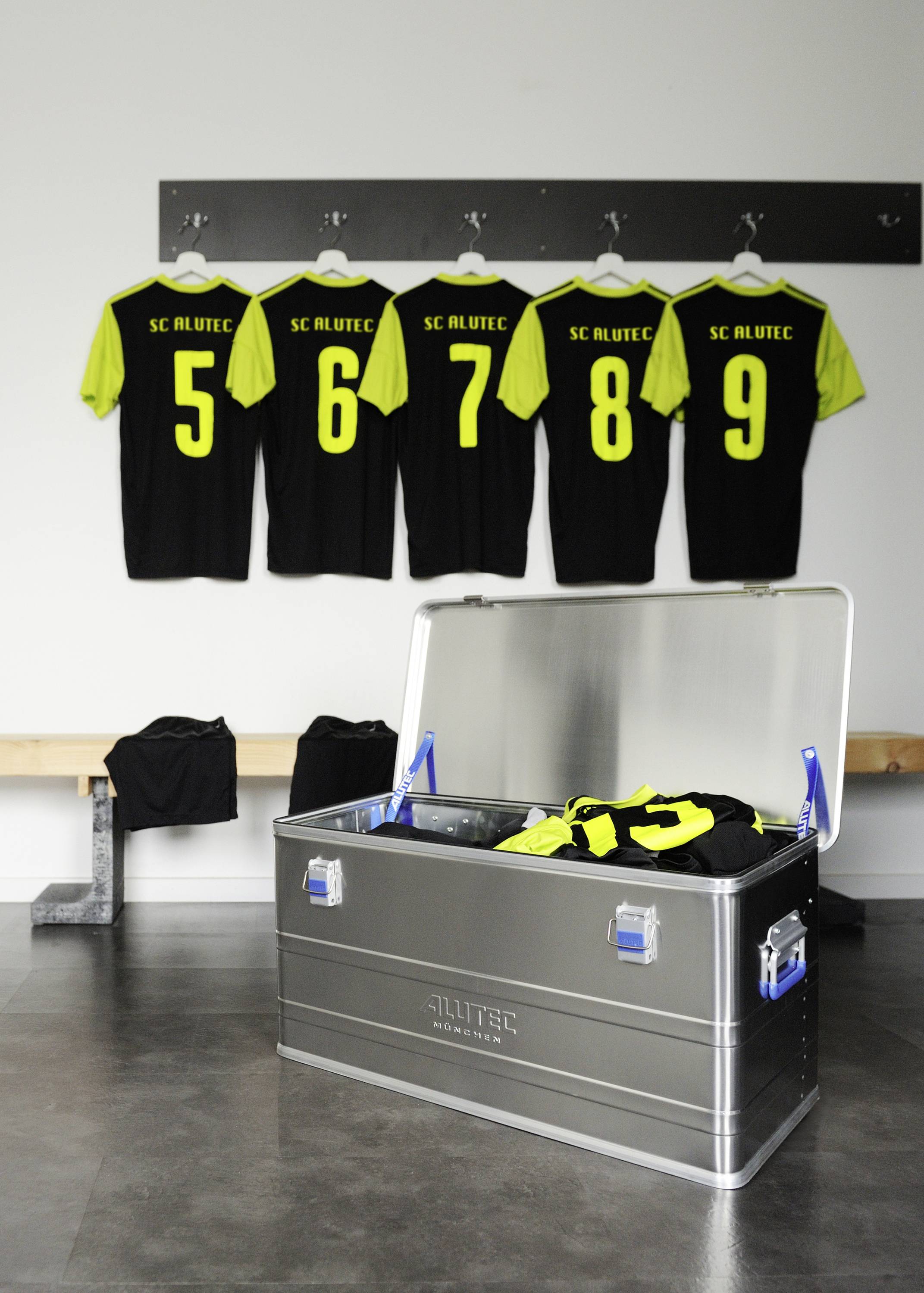 Five football jerseys with numbers 5 to 9 are hanging on the wall. An open metal box with other jerseys is in the foreground.
