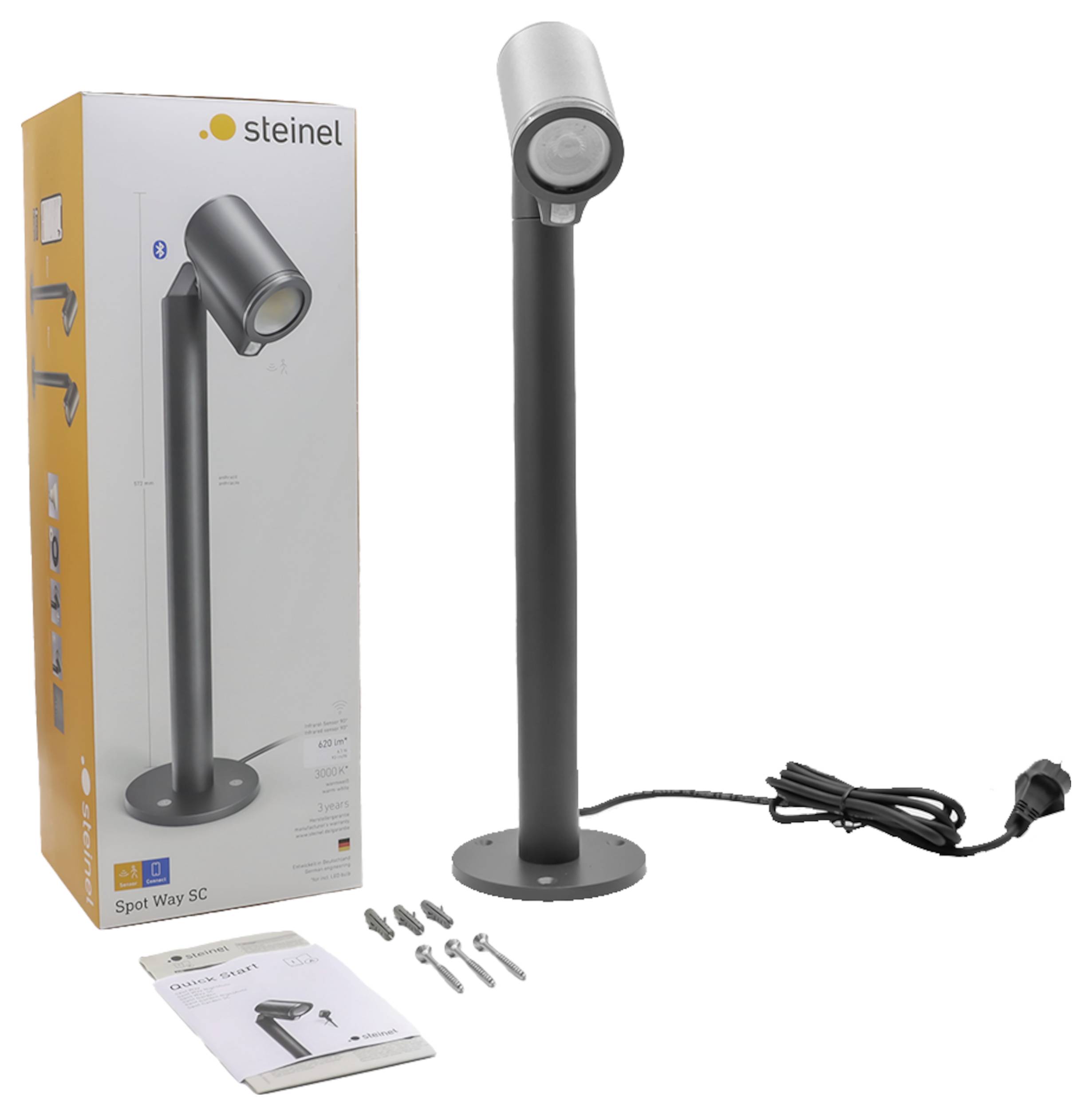 Black Steinel Spot Way SC outdoor light on a round base, shown with packaging, power cord, mounting screws, and instructions.
