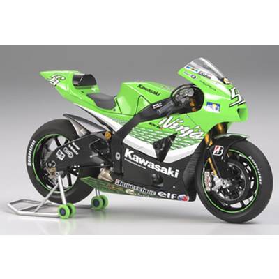 A green Kawasaki racing motorcycle stands on a stand, ready for a race. It has sponsorship decals and a race number on the fairing.