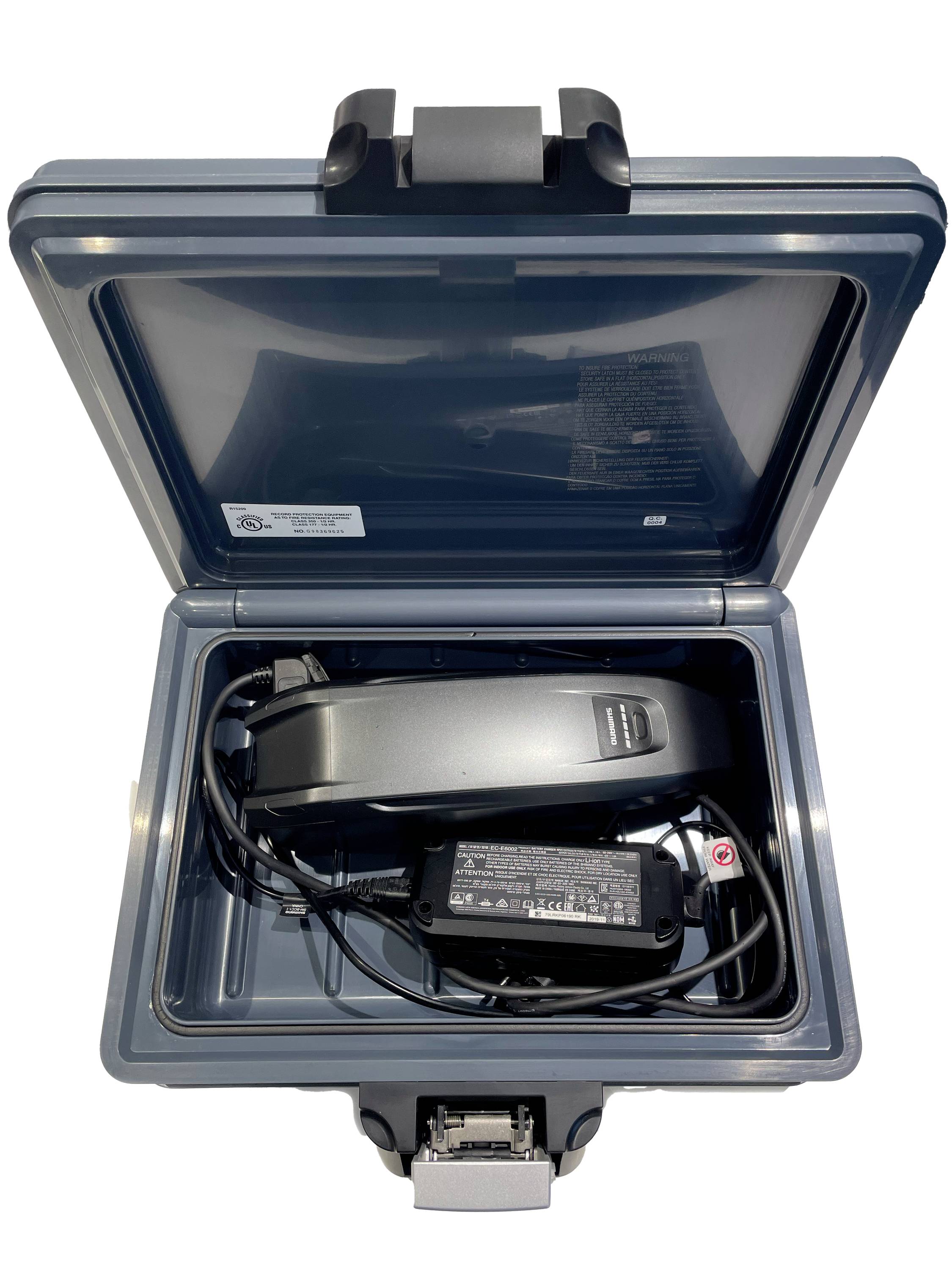 An open grey hard-shell suitcase reveals an electronic device with a power cable.