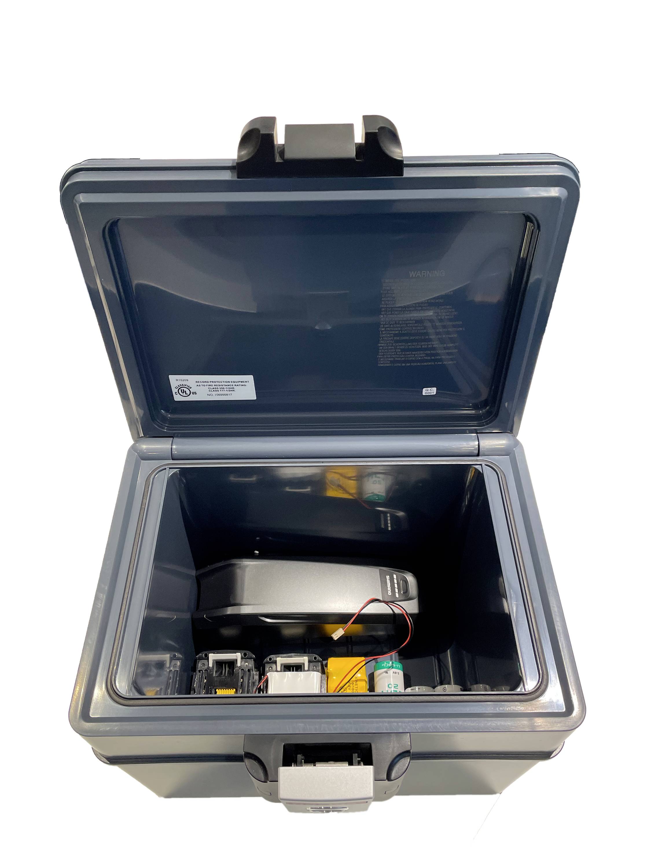 An open, square container with electronic devices and a battery inside.<br><br>Note: The translation is already in British English, as there are no specific regional variations in this technical description.