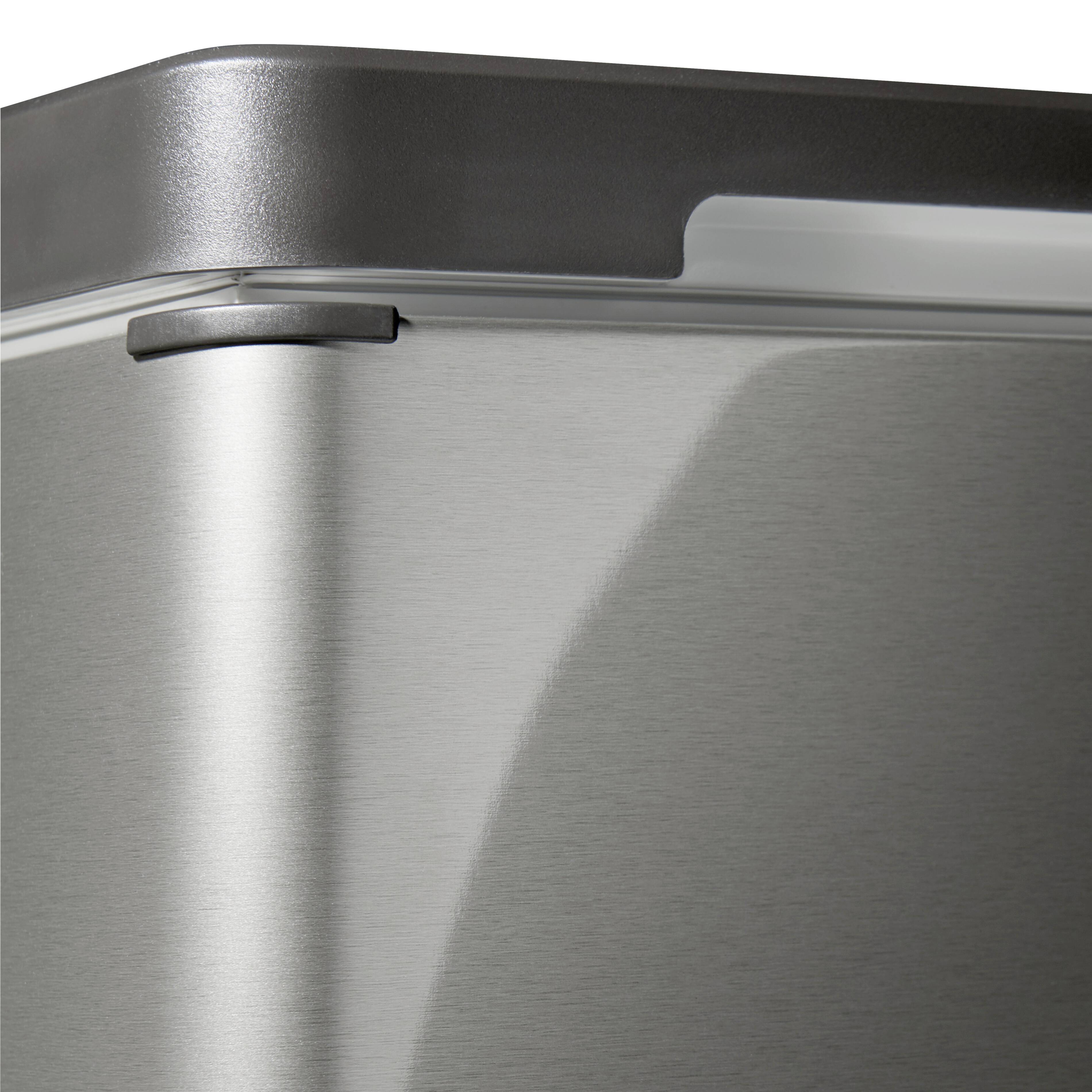 The upper section of a silver fridge, showing the top corner with rounded edges and a smooth, reflective surface.