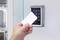 A hand holds an access card in front of an electronic keypad lock on a door, ready to use the access control system.