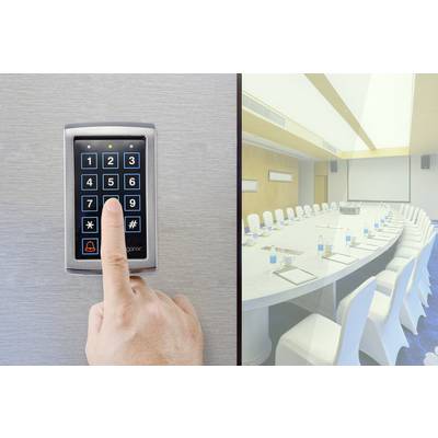 A person is pressing a button on an electronic door lock with a number pad next to an empty conference room.