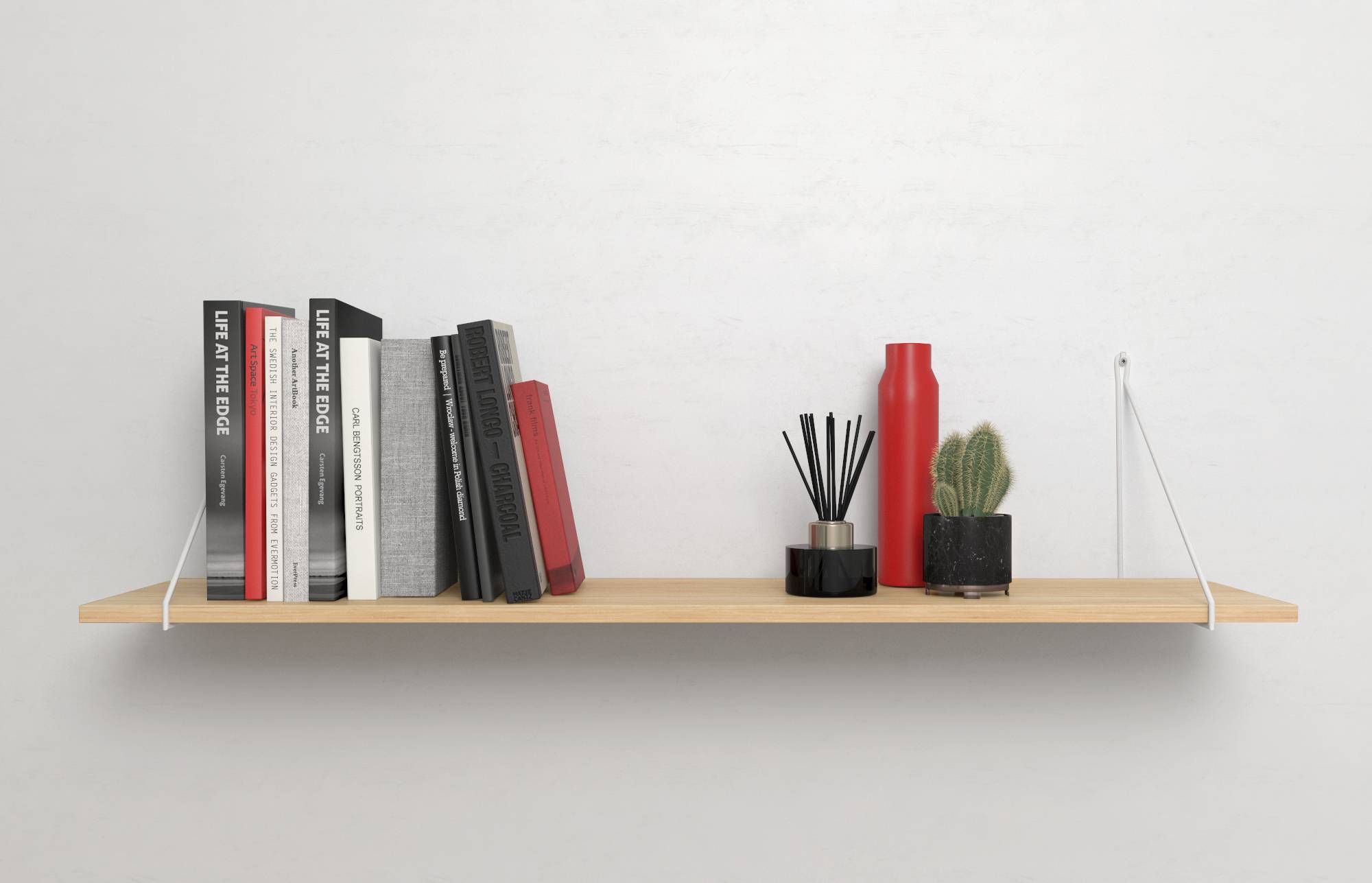 A wooden shelving unit with a selection of books on the left and decorative objects, including a cactus and red vase, on the right.