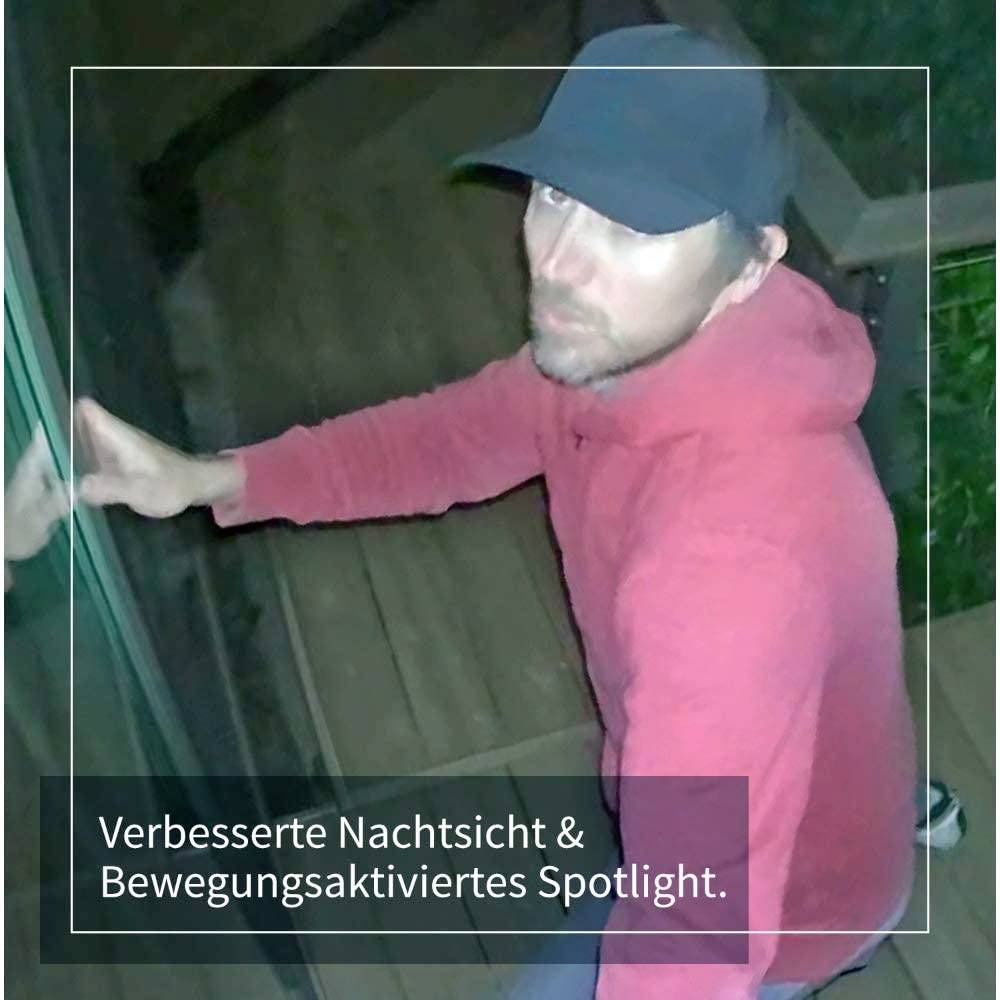 A person in a red hoodie and baseball cap stands at night in front of a glass door. Text: 'Enhanced Night Vision & Motion-Activated Spotlight.'