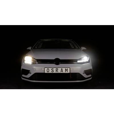 A white car with a black radiator grille and switched-on LED headlights is standing in a dark room. The number plate reads 'OSRAM'.