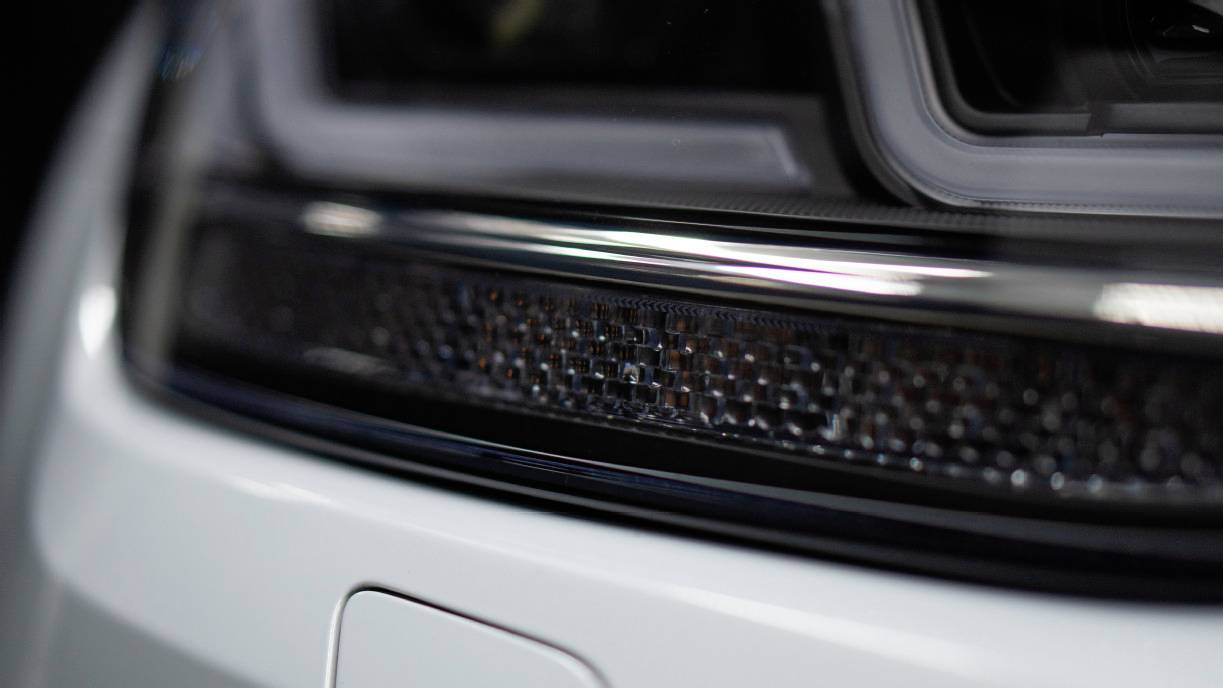 Close-up of a modern car headlight with clean lines and an elegant curve, indicating advanced vehicle design.