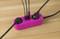 A pink multi-socket extension lead on a wooden table, with several black cables plugged in, enabling efficient power connections.