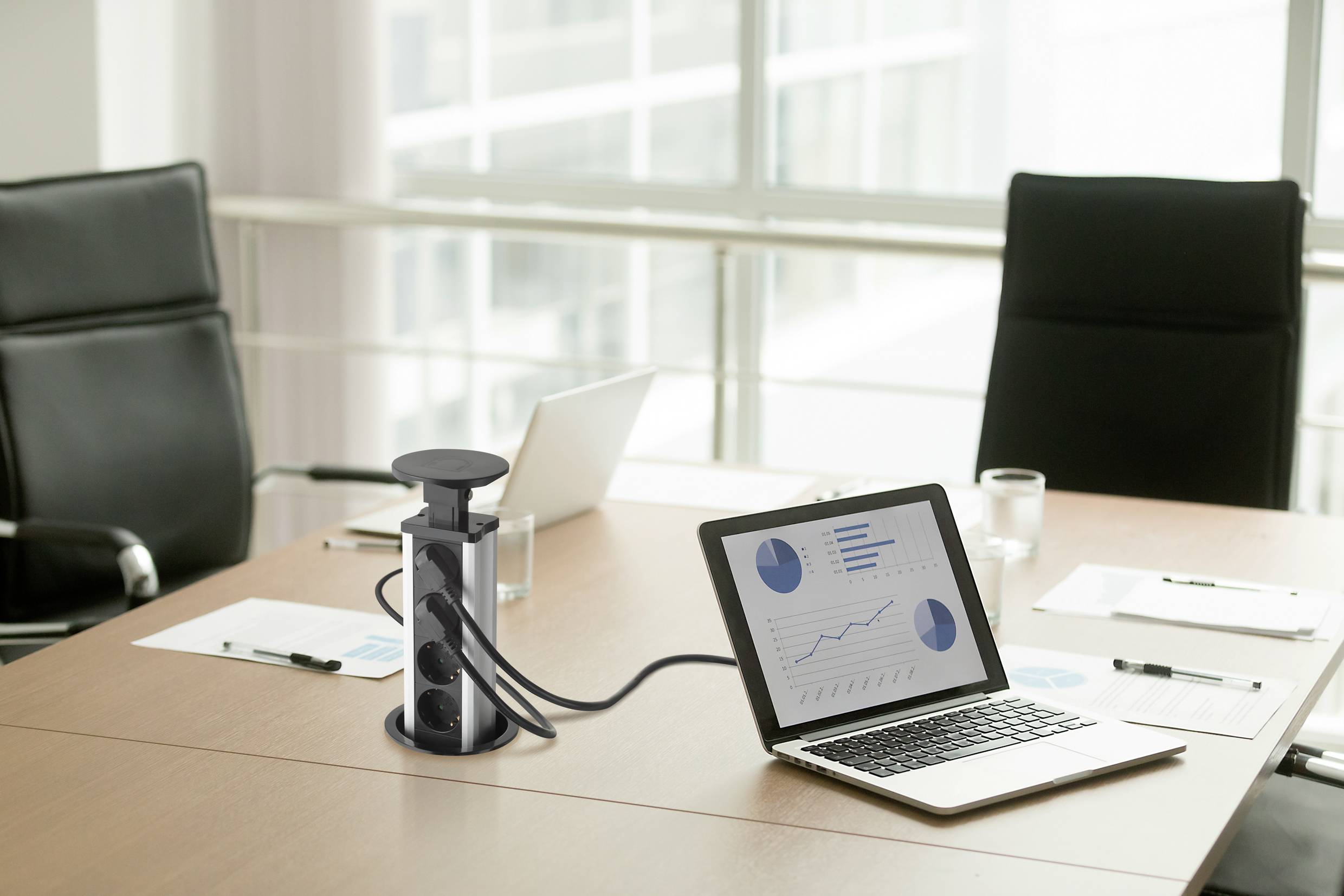 Conference room with a table, on which a laptop is displaying diagrams. Next to it are notes and a glass of water.