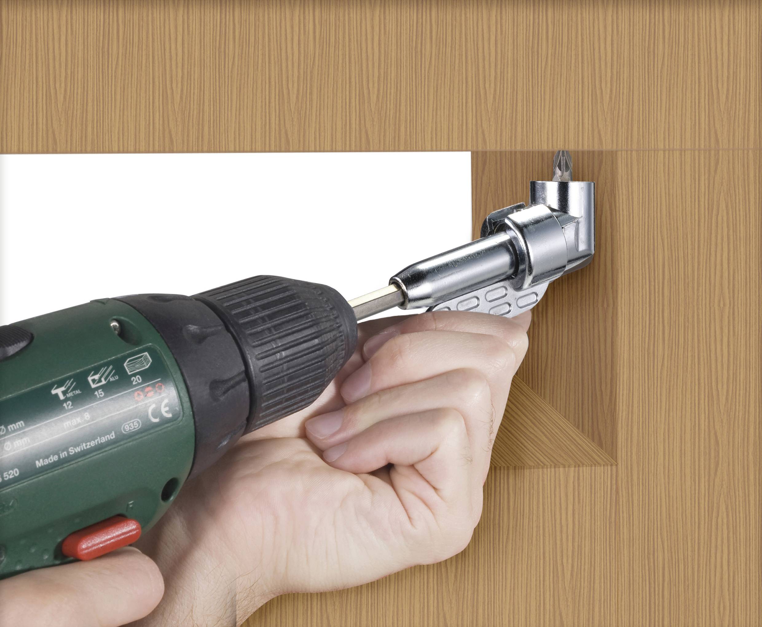 A hand is holding a cordless drill with an angle adapter to drill in a confined space.