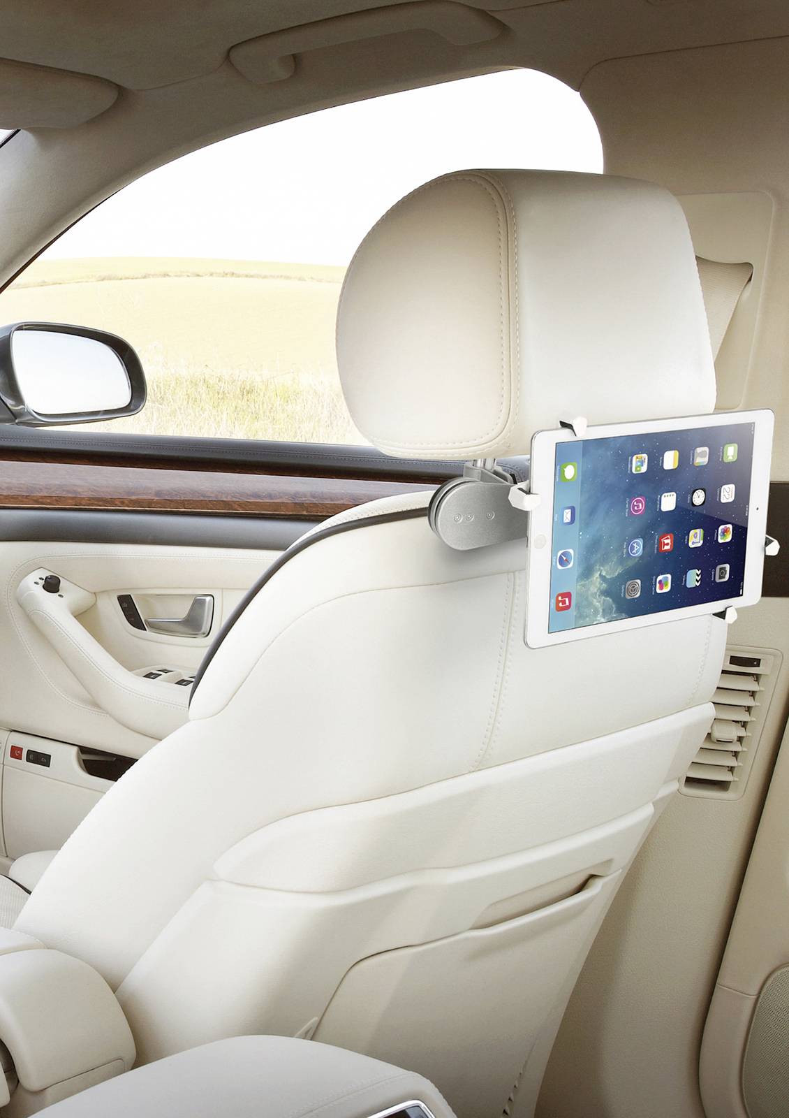 A tablet is mounted on the back of a car seat. Various app icons are visible on the screen.