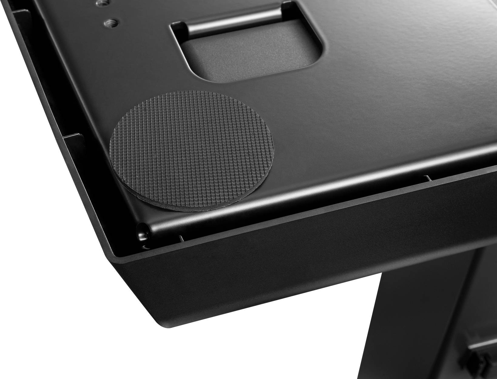 Black gaming desk detail with non-slip round mat in the corner, steel frame.