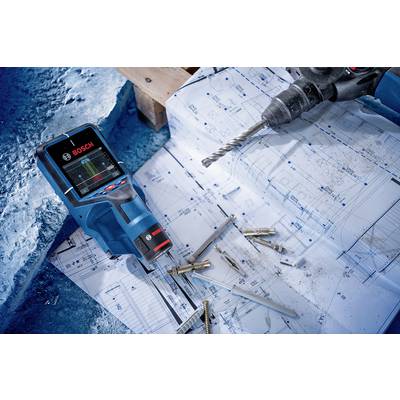 A Bosch scanner lies on building plans next to a drill and several screws. Construction site situation with technical details.