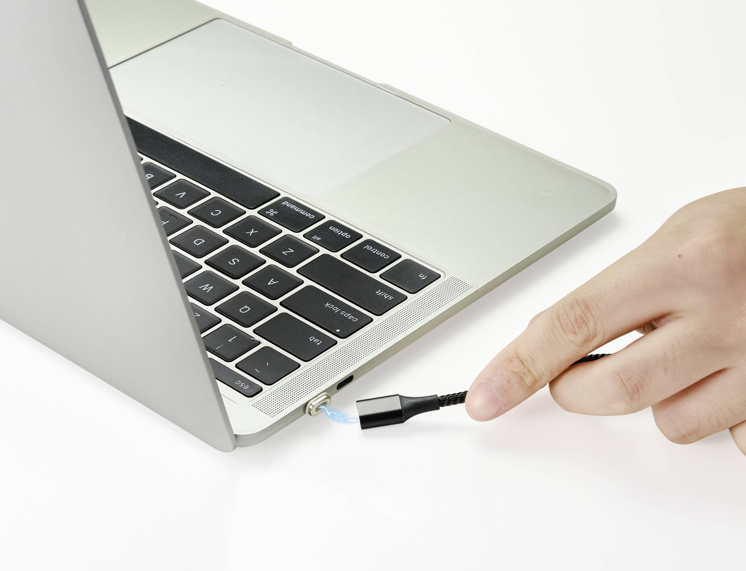 A hand is inserting a network cable into a laptop. The laptop is open, and the cable is being connected on the left-hand side.